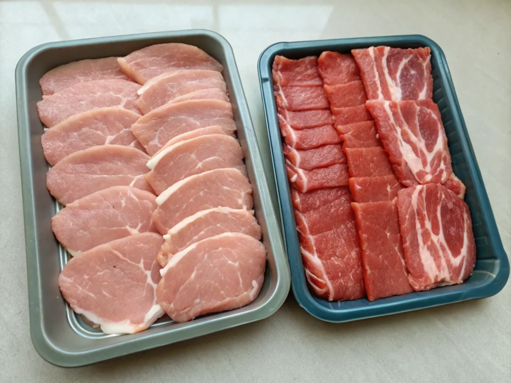 Two separate trays of meat, one tray with halal cuts and another with non-halal cuts.