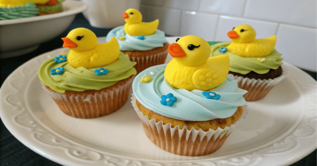 A close-up of rubber duck cupcakes with vibrant fondant decorations.